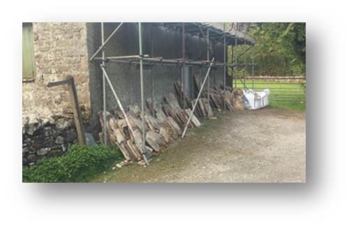 An image of the stone slate stacked in size order as it was removed from the roof ready to be measured and lifted back up once the new timber frame is ready to receive it.