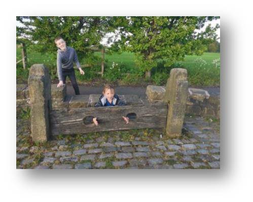 In the stocks where she belongs, Emily checks out how punishments worked in the old days.